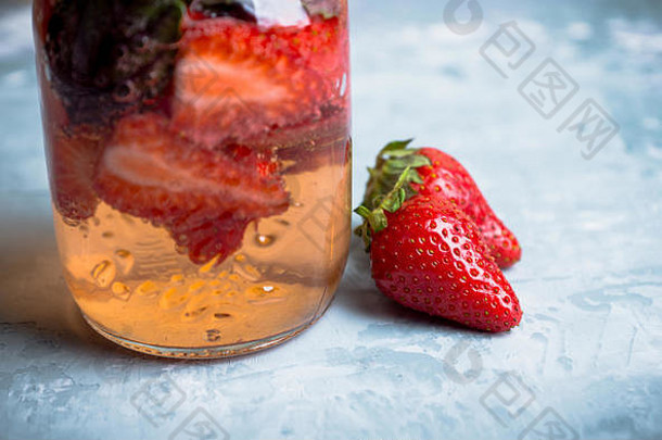 在玻璃杯中加入草莓和罗勒的新鲜鸡尾酒。浅景深。