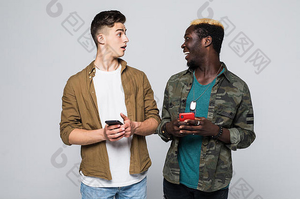 两个不同种族的朋友在白色背景下单独使用手机