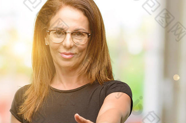 身穿黑色衬衫、戴眼镜的中年妇女以握<strong>手姿势</strong>握<strong>手</strong>表示欢迎，表达信任和成功理念，并致以问候