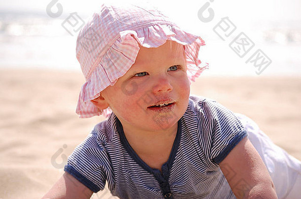 在海滩上蹒跚学步的孩子戴着太阳帽