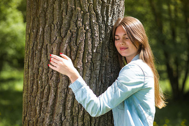 年轻的女人拥抱大树爱自然概念