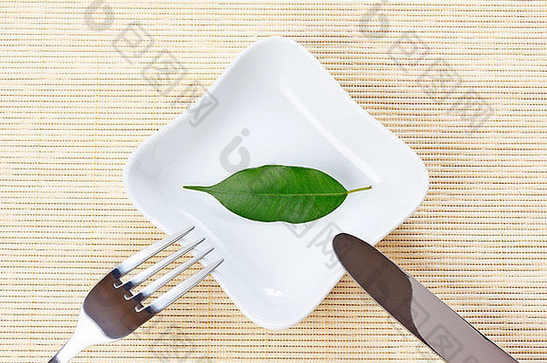 盘子上的绿叶作为素食-健康饮食的概念