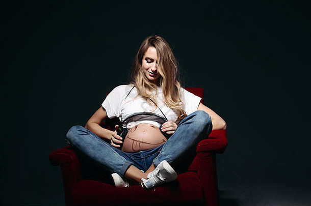 孕妇坐在椅子上，展示腹部和姿势。