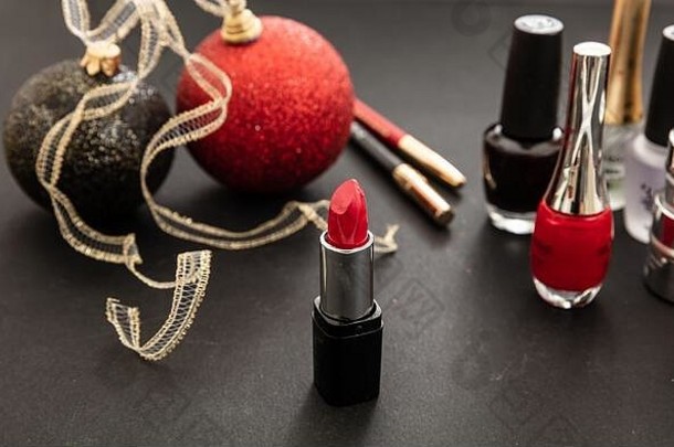 化妆圣诞派对概念。在黑色背景下用红色和黑色来装饰产品和圣诞球。除夕准备