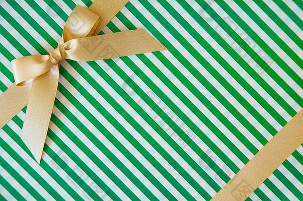 白色和绿色背景上带有蝴蝶结的金丝带作为礼物