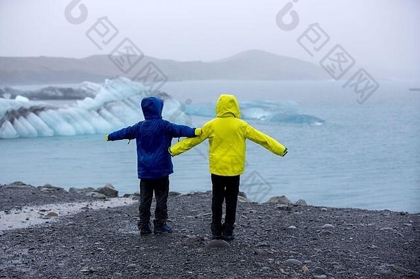 一个雨天的傍晚，孩子在冰岛风景如画的冰山环礁湖约克萨隆拍照
