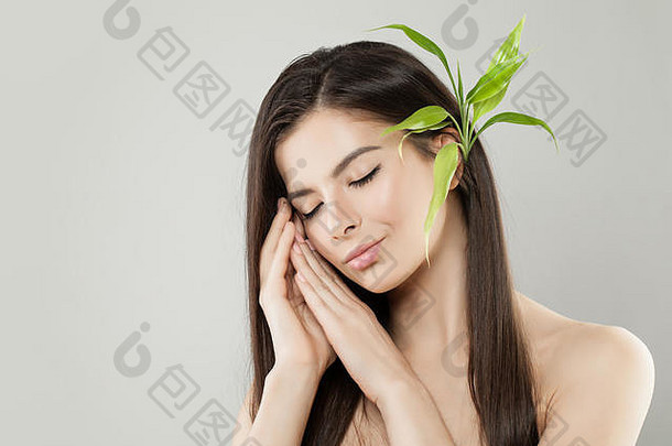 头上戴着绿色竹叶的美丽放松的女人。完美的头发和健康的皮肤