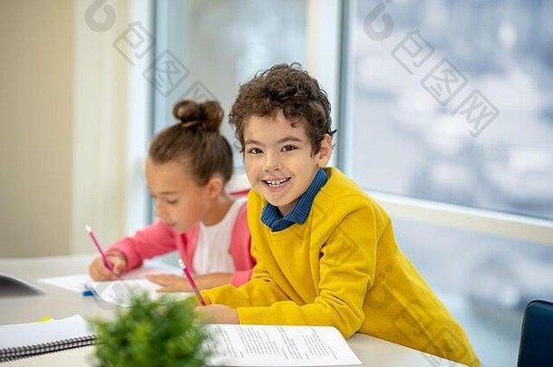 一个面带微笑的男生正在努力完成他的作业