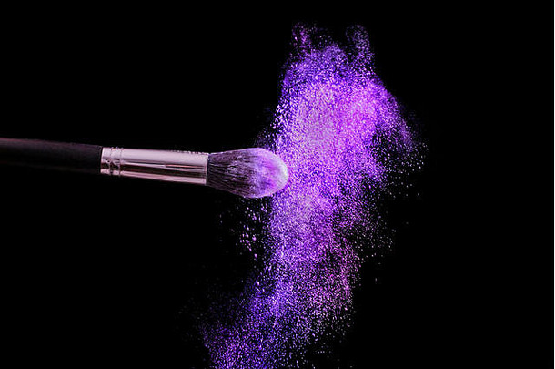 使刷粉爆炸紫色的灰尘颜色孤立的黑色的背景