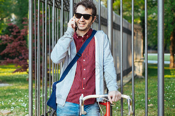 年轻的成人男人。会说话的移动电话城市城市公园背景