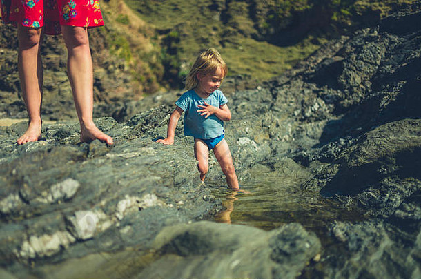 蹒跚学步的玩岩池海滩妈妈。