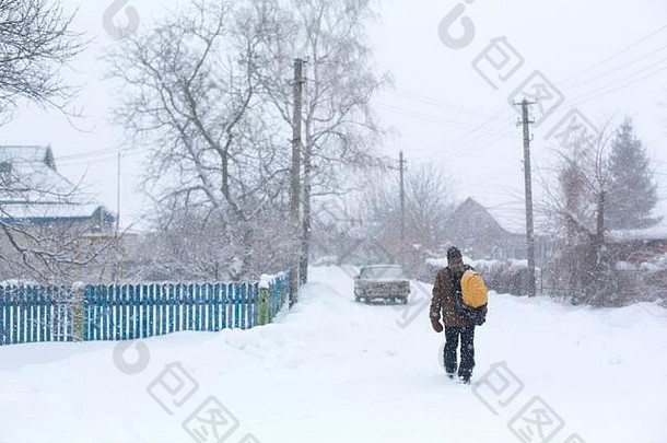 冬天，一个乡下人背着一个黄色的背包走在街上。暴风雪。