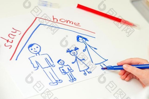 孩子在家里的白纸上用“呆在家里”这几个字画着幸福的家庭。儿童的创造力。