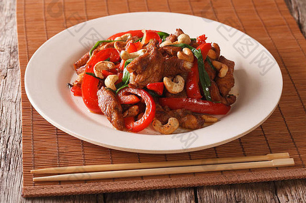 泰国菜：炸鸡配蔬菜和腰果，放在桌上的盘子里。水平的
