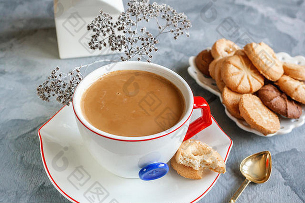 早餐热巧克力装在原汁原味的白色杯子里，饼干的背景上有一个蓝色的按钮。令人振奋的早餐。