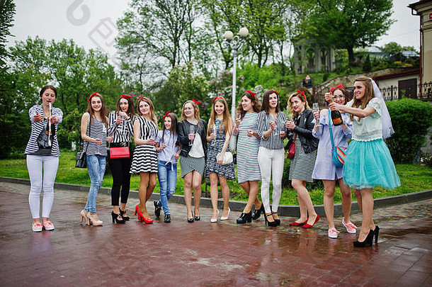 十一位漂亮的辫子女郎和可爱的新娘在公园里用香槟庆祝单身派对。