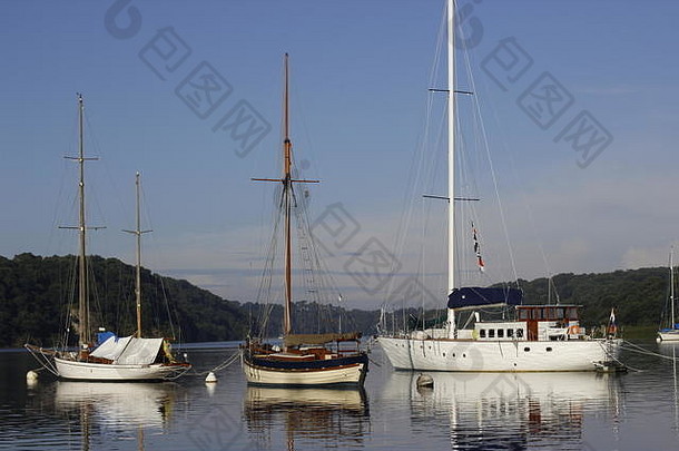 停泊在码头上的游艇展现了蔚蓝的天空和水面上桅杆和索具的倒影