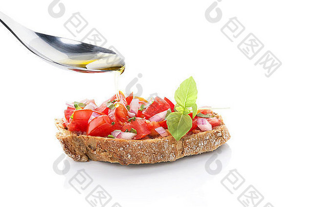 橄榄油从银勺滴到布氏面包上，加入切碎的西红柿、洋葱和新鲜香草。烹饪。