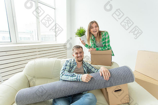 一对幸福快乐的年轻夫妇坐在新公寓的客厅里，强壮的男人和漂亮的女人手里拿着他们的东西
