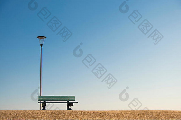 废弃的休息长凳，灯柱在柏油路上，临摹空间映衬蓝天，孤独感概念