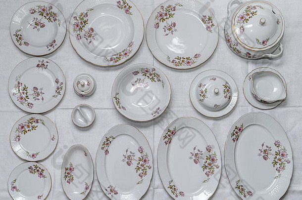 一套复古陶瓷工厂手工制作的餐具，白色桌布上有颜色微妙的花朵，16件，俯视图