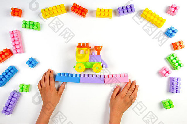 孩子手玩色彩斑斓的塑料建设块火车白色背景