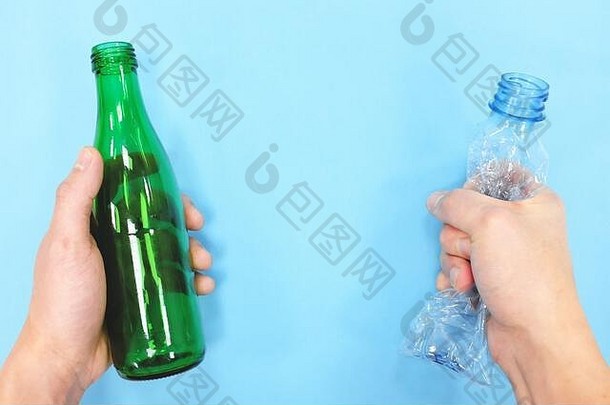 手持有空塑料玻璃瓶蓝色的背景绿色概念玻璃与塑料容器