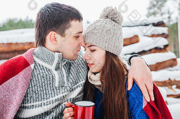 在冬季森林里喝热饮的年轻浪漫情侣。相爱的夫妻