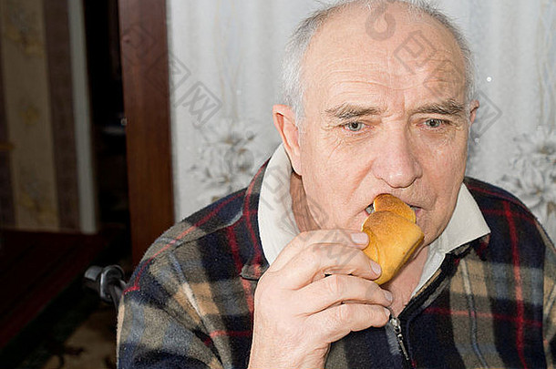 老人沉思着，一边吃着刚烤好的面包卷，一边<strong>回忆往事</strong>，一边若有所思地盯着镜头
