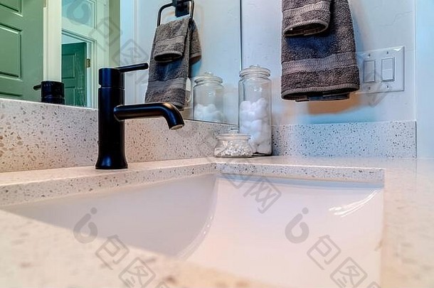 浴室内带黑色水龙头的底部水槽，镜子和毛巾靠墙