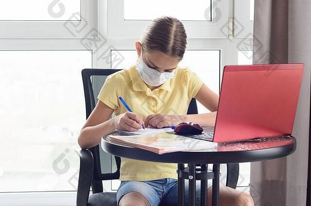一个感染病毒的女孩在家接受远程教育，并在笔记本上写字