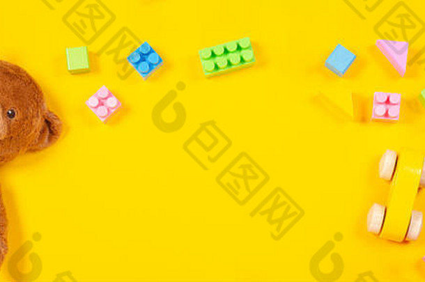 玩具架上有泰迪熊、木制玩具车、黄色背景上的彩色立方体。俯视图