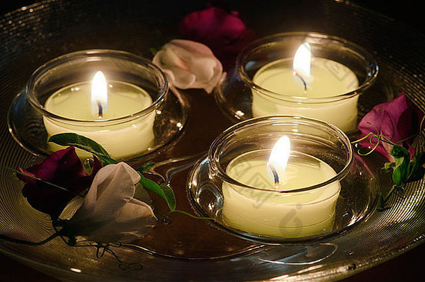 三支燃烧的蜡烛和一碗水里飘着的甜豌豆花