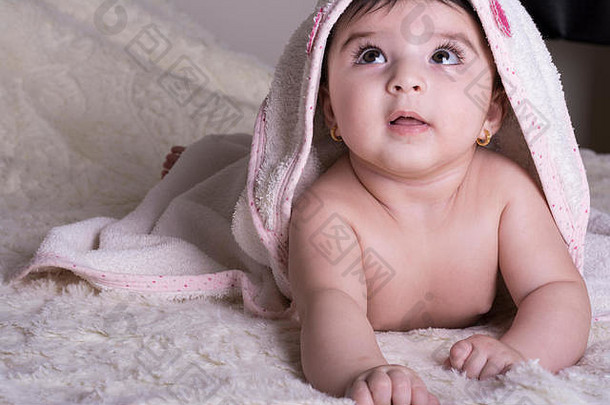 小宝宝穿着白色浴巾，洗澡或淋浴后躺在床上休息。儿童托儿所。儿童用纺织品和床上用品。