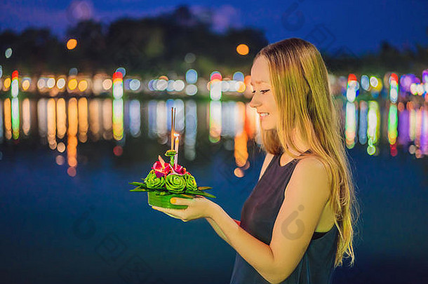 这位年轻女子在水上跑步，庆祝洛伊·克拉通。Loy Krathong节日，人们购买鲜花和蜡烛点燃并漂浮在水面上庆祝