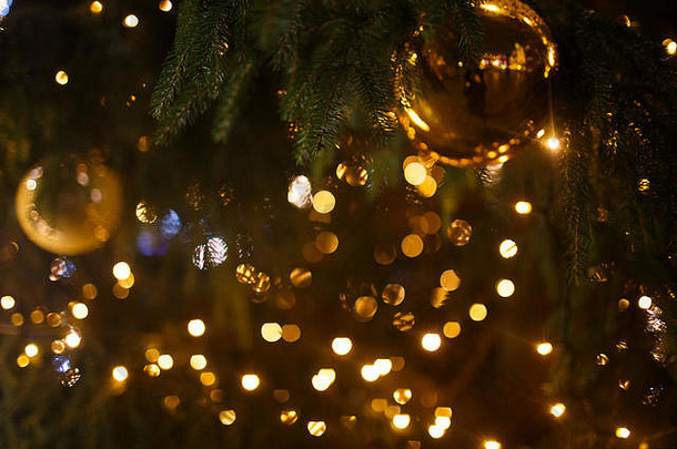 装饰圣诞树特写。金球和手电筒照明的花环。与博克的新年深色微距照片。寒假轻十二月