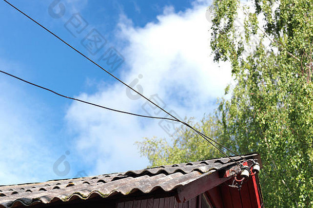 老房子用纠结的电线顶着蓝天，概念上有短路的危险