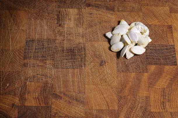 橡木砧板上的一小簇干南瓜籽。厨房，烹饪，健康饮食，宏观照片。苏格兰，英国。