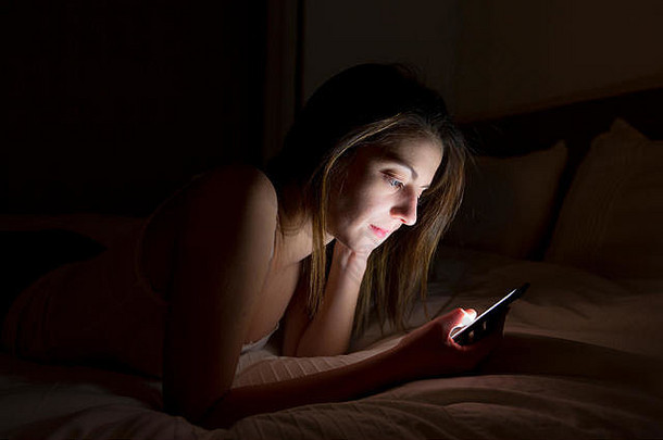 晚上在床上使用智能手机的女人