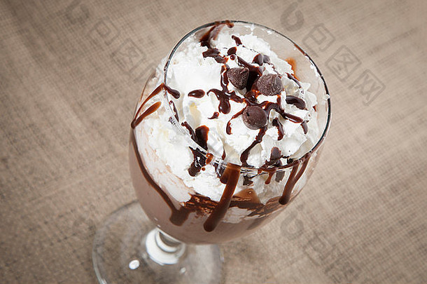 一个玻璃杯里装满了巧克力鸡尾酒，上面是鲜奶油、巧克力糖浆和巧克力片