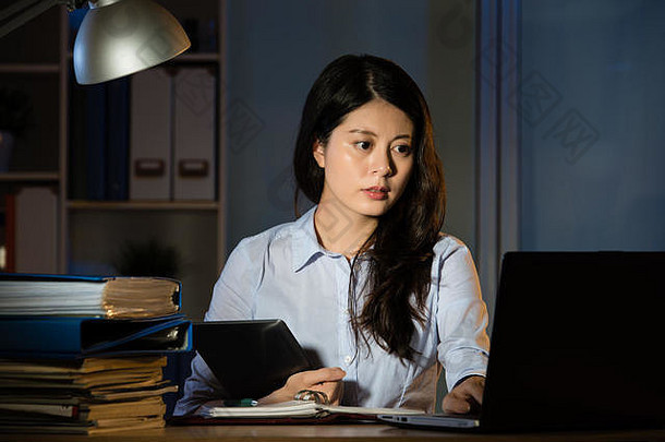 亚洲业务女人触摸屏幕数字平板电脑工作加班晚些时候晚上在室内办公室背景