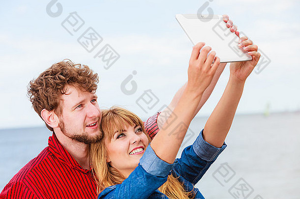 <strong>科技节</strong>日与快乐理念。年轻夫妇在海边户外用平板电脑自拍