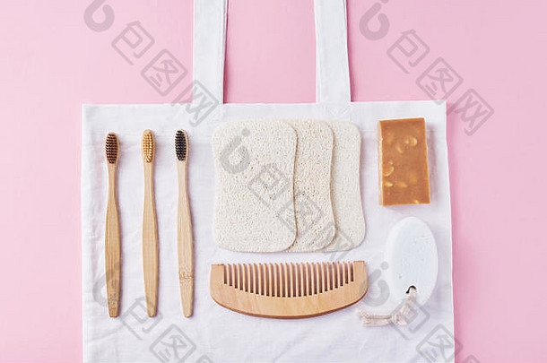 身体护理天然木质环保产品，粉色背景，平面俯视图。竹制牙刷、木梳、肥皂、海绵和天然洗涤剂