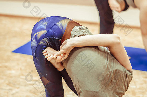 穿着运动服的漂亮女孩正在体育馆的瑜伽垫上做瑜伽