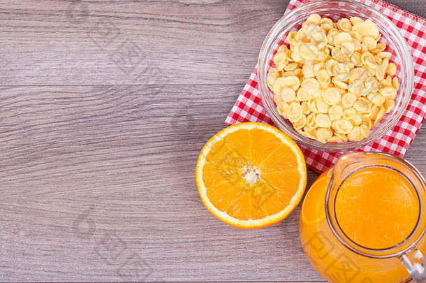 木质背景上的玉米片、橙子和鲜榨橙汁。为文本留出空白。顶视图。