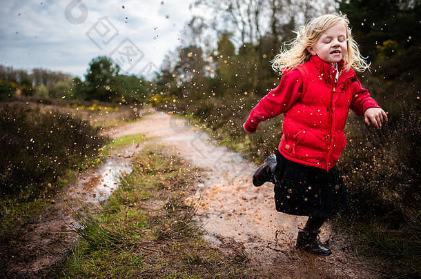 女孩走运行跳跃泥泞的水坑农村家庭走穿温暖的红色的身体温暖的