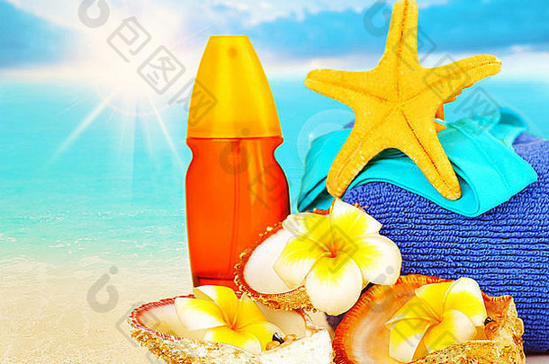 蓝色海洋背景上沙滩上的沙滩用品、防晒霜、黄海星、贝壳、法国花