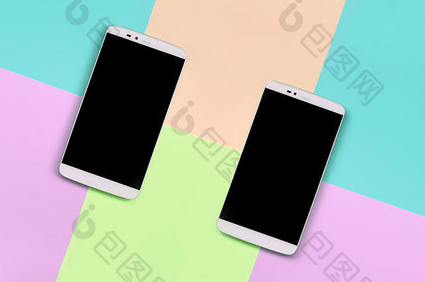 两款现代智能手机，黑色屏幕，以时尚柔和的粉色、蓝色、珊瑚色和石灰色纸张为背景，简约概念。
