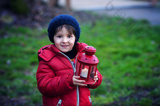 可爱的孩子，在一个阳光明媚的冬日，在公园里提着红灯笼，在户外