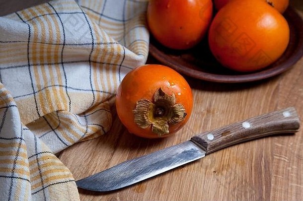 由成熟美味的新鲜<strong>柿子</strong>果实和木制背景的复古刀组成。